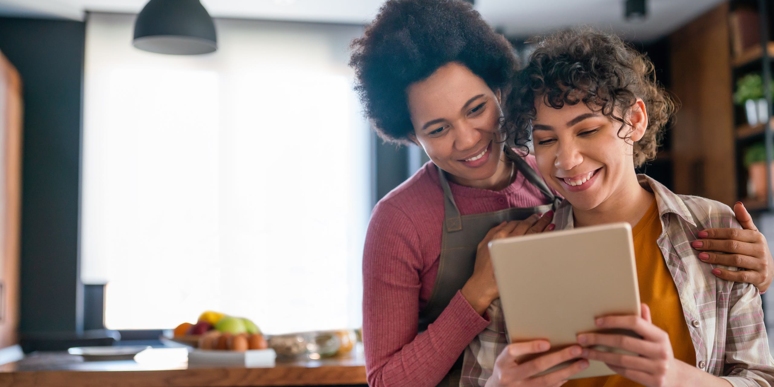 Happy multiethnic parents and kid having fun while cooking and following recipe on the internet.