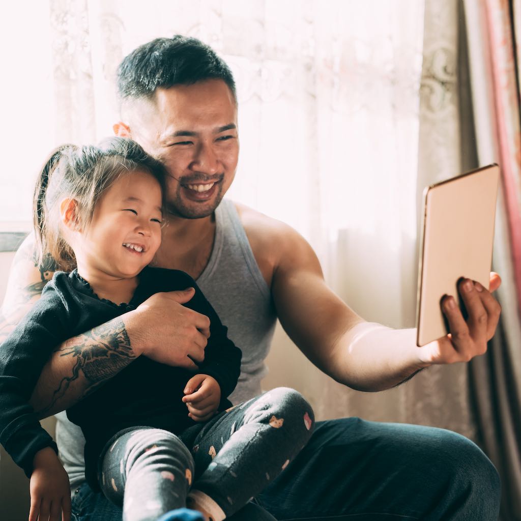 Parent holding their child and iPad